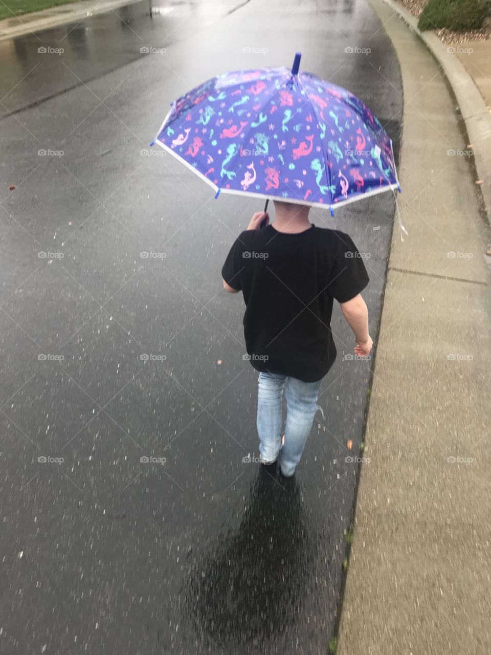 Taking a stroll barefoot in the rain, keeping dry with an umbrella. 