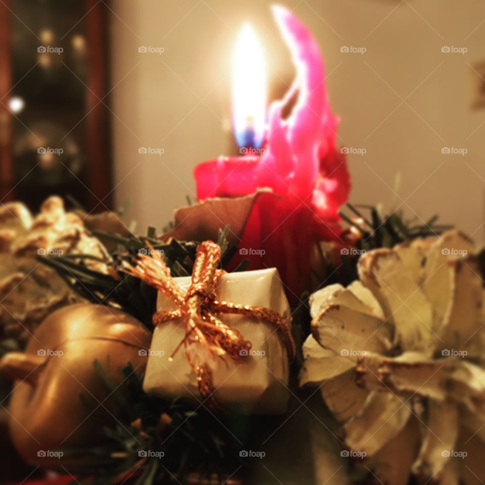 Candle burning with flowers surrounding it during the holidays 