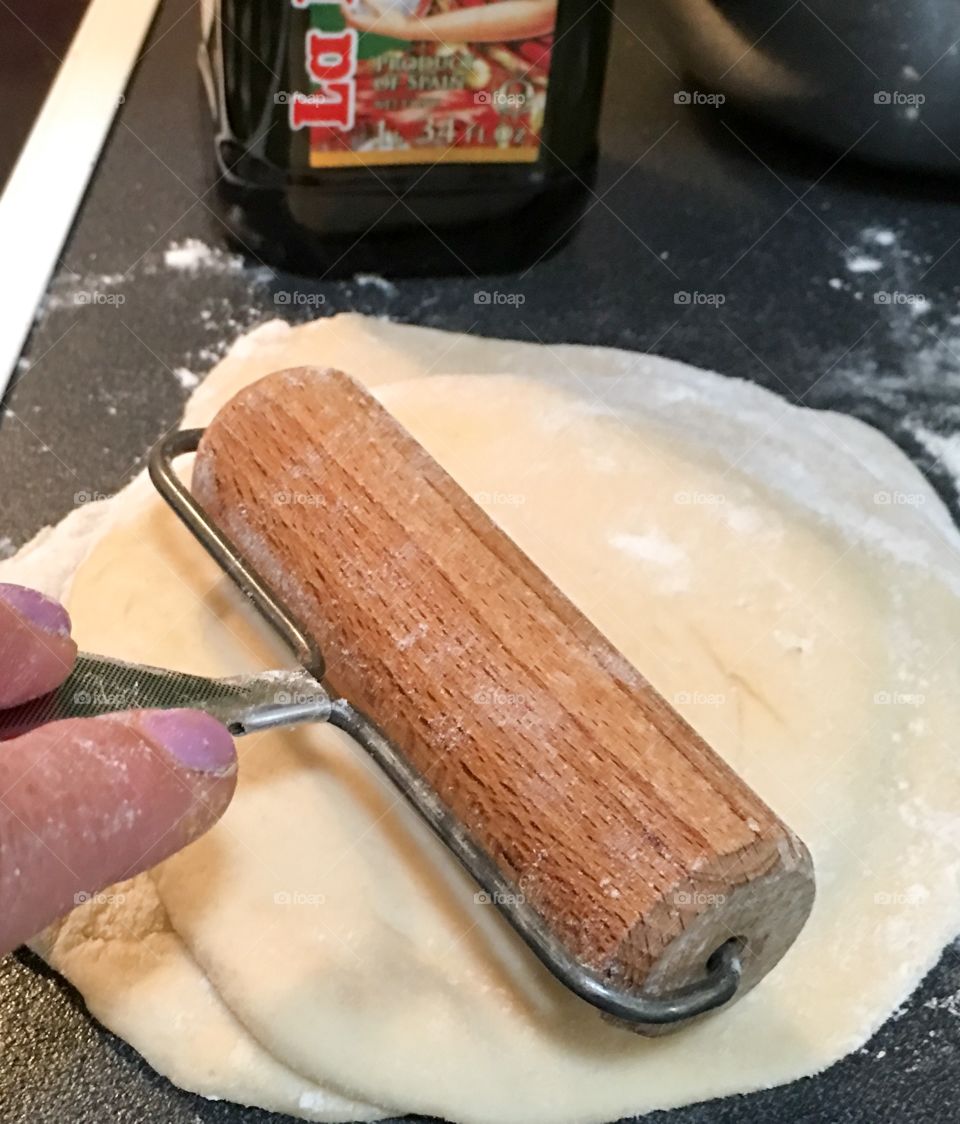 Handy woman in kitchen rolling bread dough for homemade pita bread