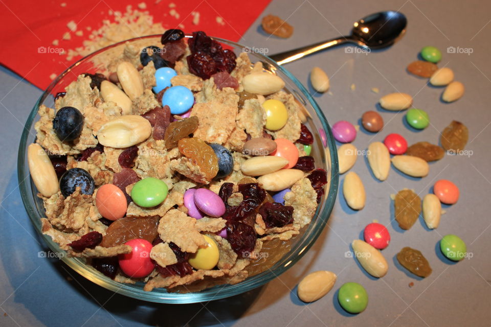 A bowl full of flakes,almonds,dry fruits and colorated candy