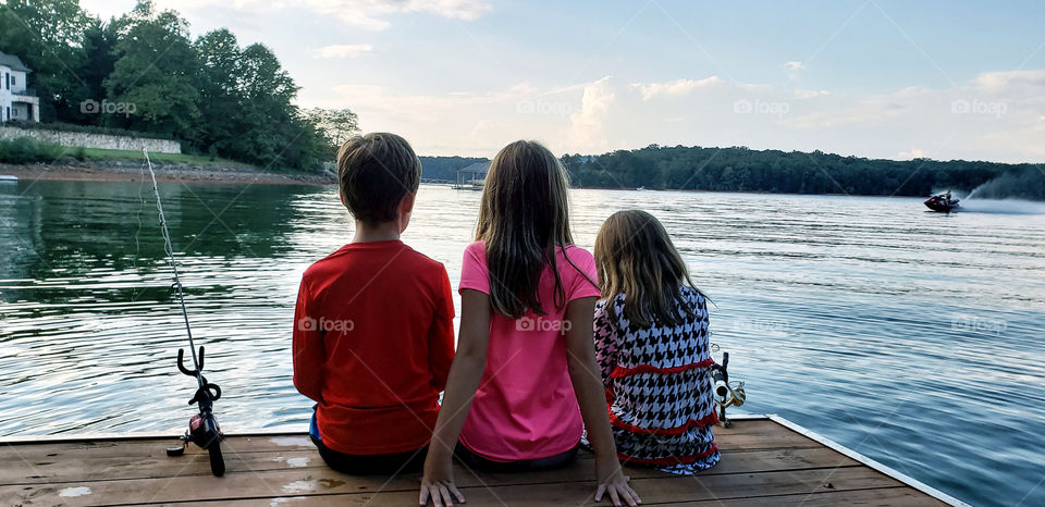 three kids on a lake dock.