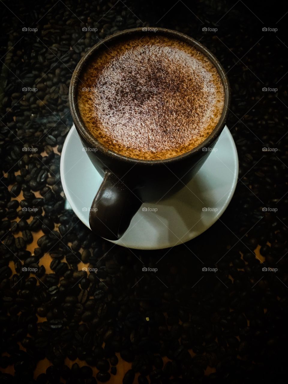Elevated view of coffee in cup with coffee beans