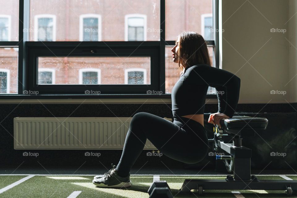 Young brunette woman training her muscles in the fitness club gym