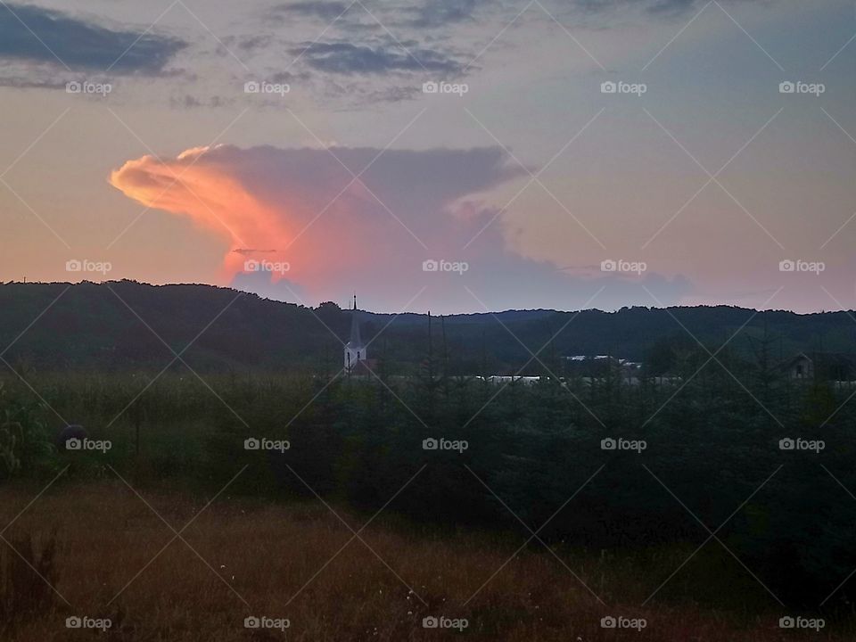 Distant thunderstorm over the Romanian countryside. The storm is beautifully illuminated by the setting sun.