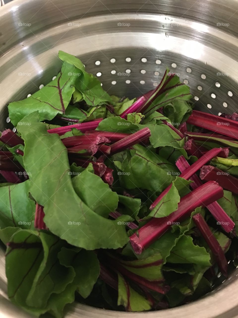 Beet greens in a stainless steel colander