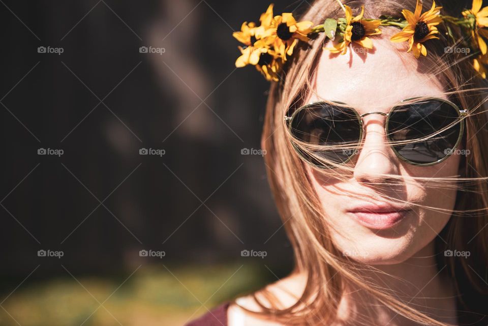 Selfie photo of a millennial woman wearing a flower crown and sunglasses outdoors 