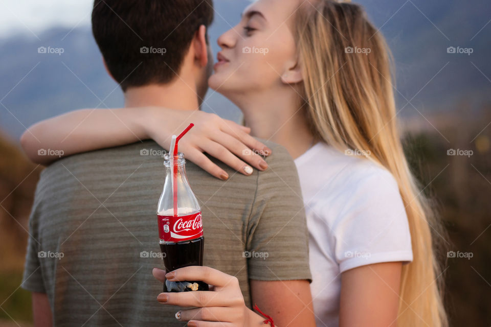 Teenage girl kissing boy and holding drink