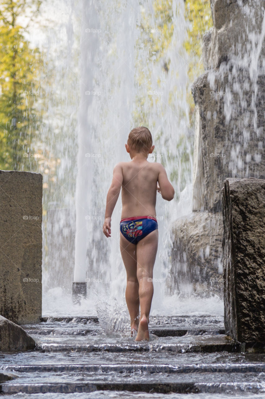 a boy playing in fountain