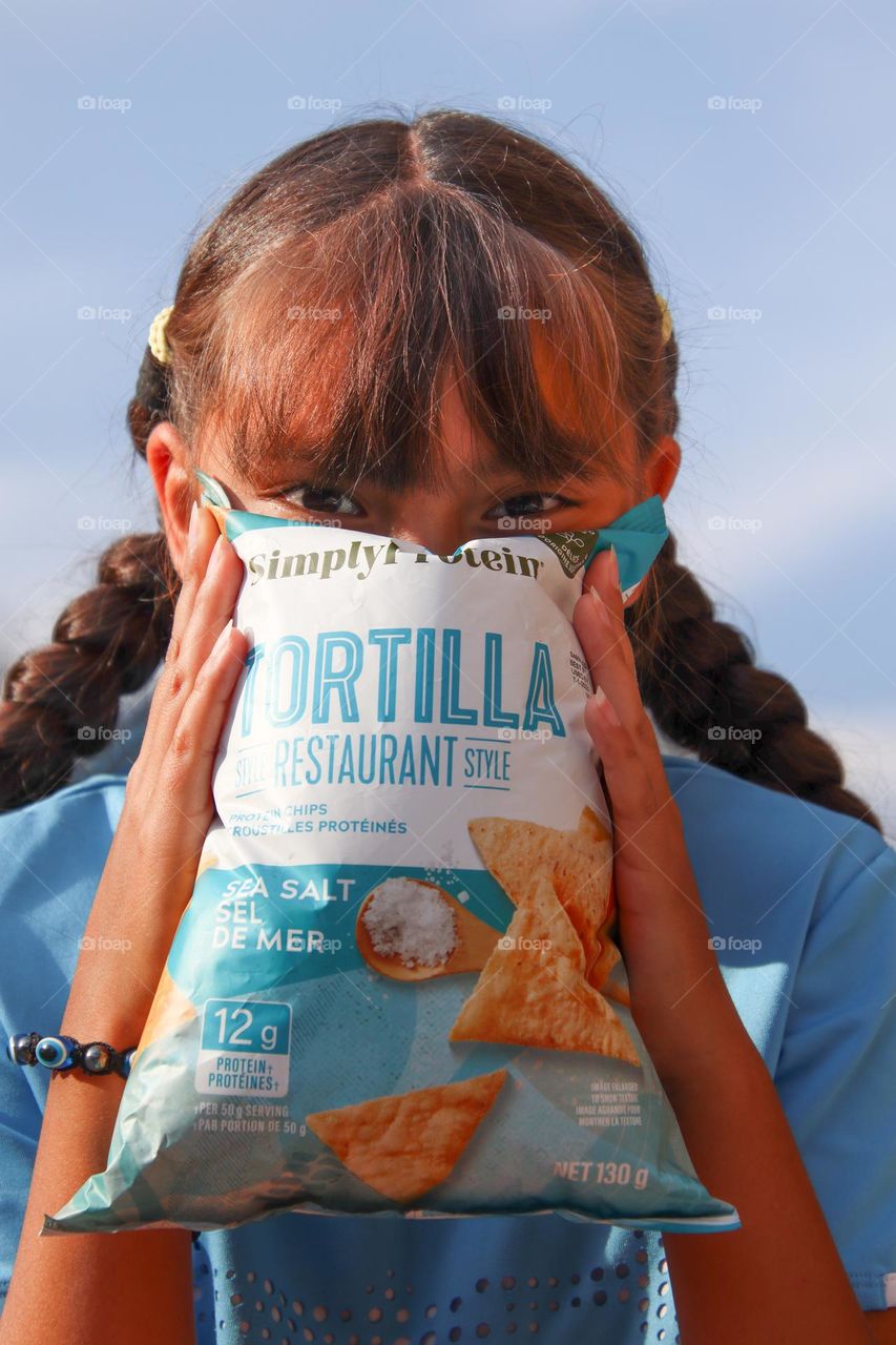 Cute happy girl with a bag of chips