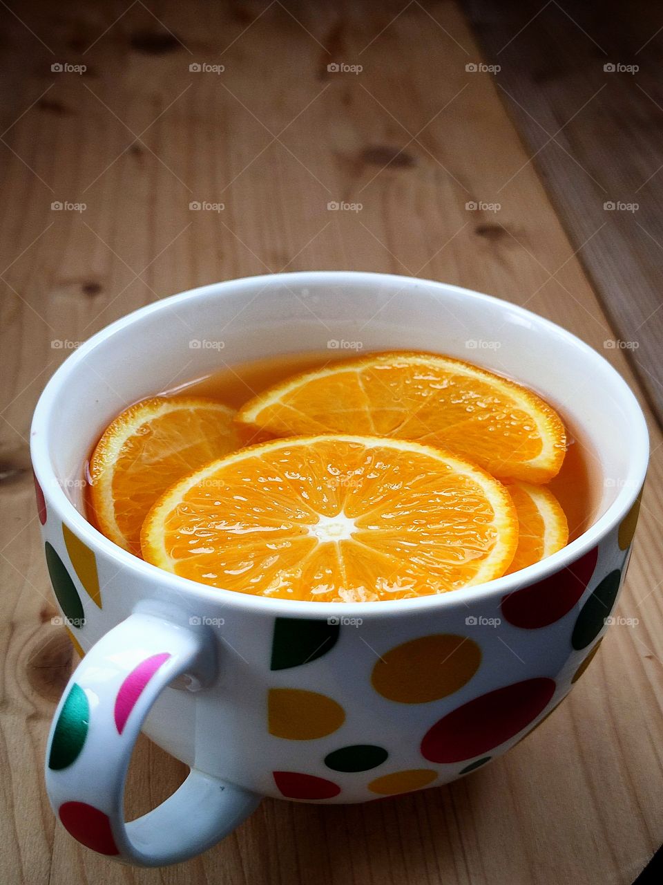 Sliced ​​oranges in a colored mug with water.  Toning and vitamin drink