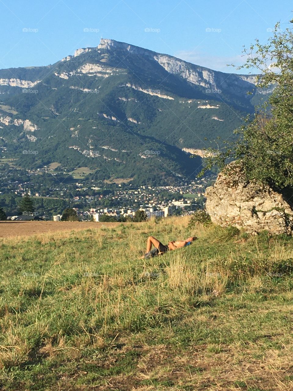 Magical outside : young man chilling in sunny meadow admiring mountains after first quarantine 