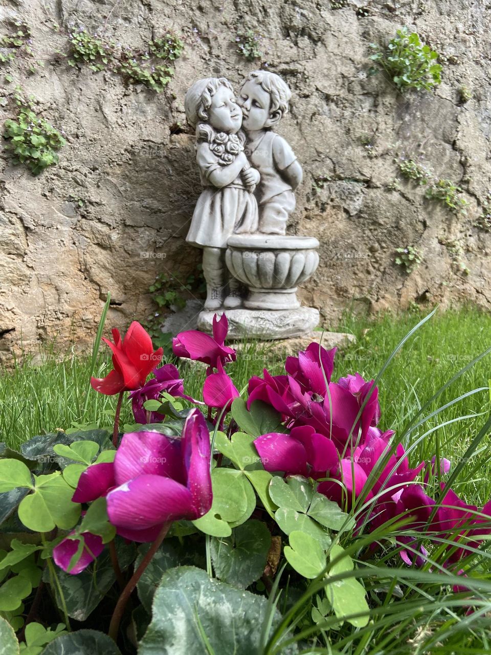 Nothing says Spring more than new love and flowers. Springtime flowers blooming in front of a statue of a boy kissing a new love.