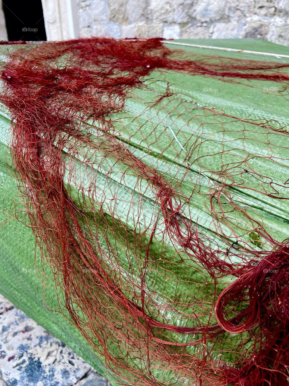 A red fishing net against a green boat representing at simple times of day’s gone by.