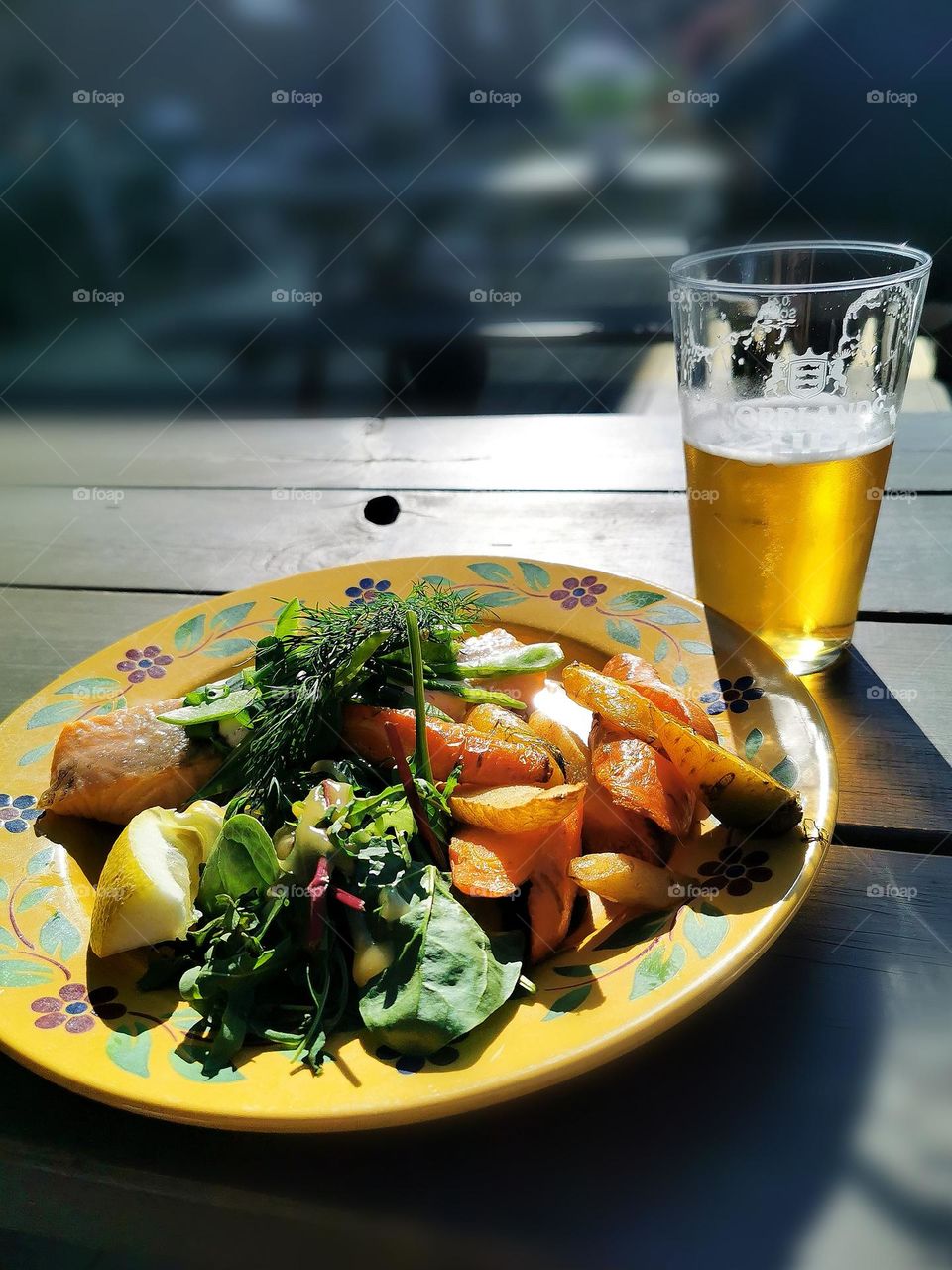 Food on a yellow plate and a glass of beer