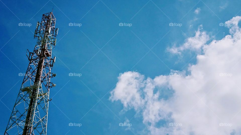 Equipment on mobile phone tower with cloudy blue sky background