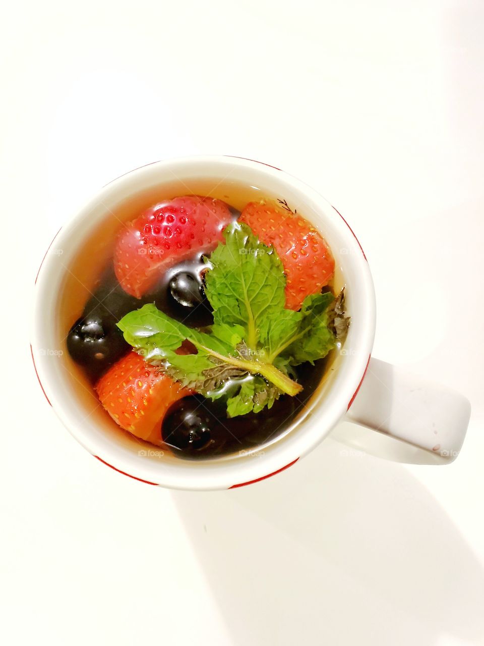 Hot tea with blueberries, mint, and strawberries in a glass. Warming tea, healthy fruit infused tea. closeup view