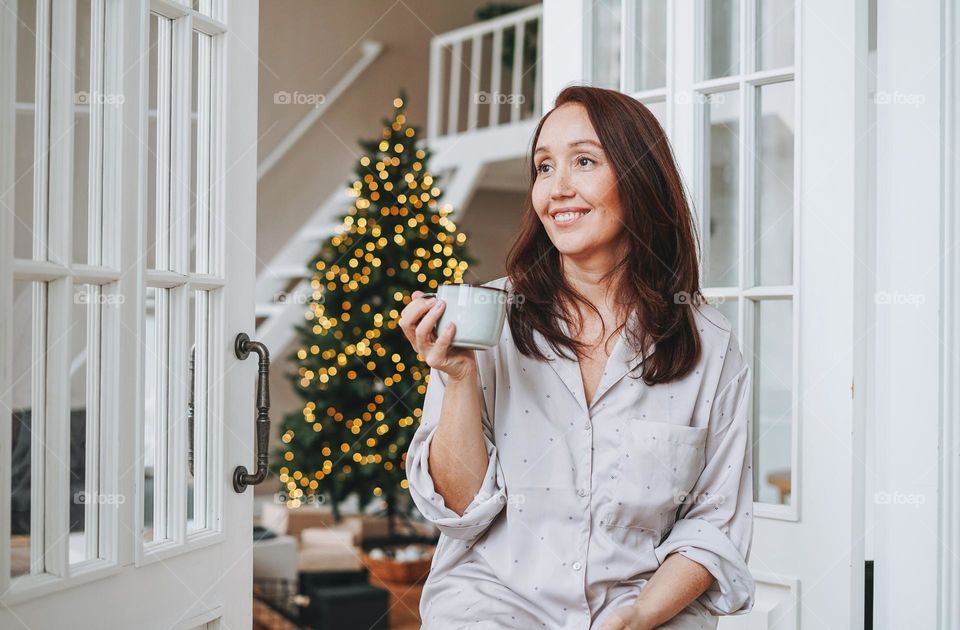 Beautiful woman with cup of hot drink at home in Christmas time 