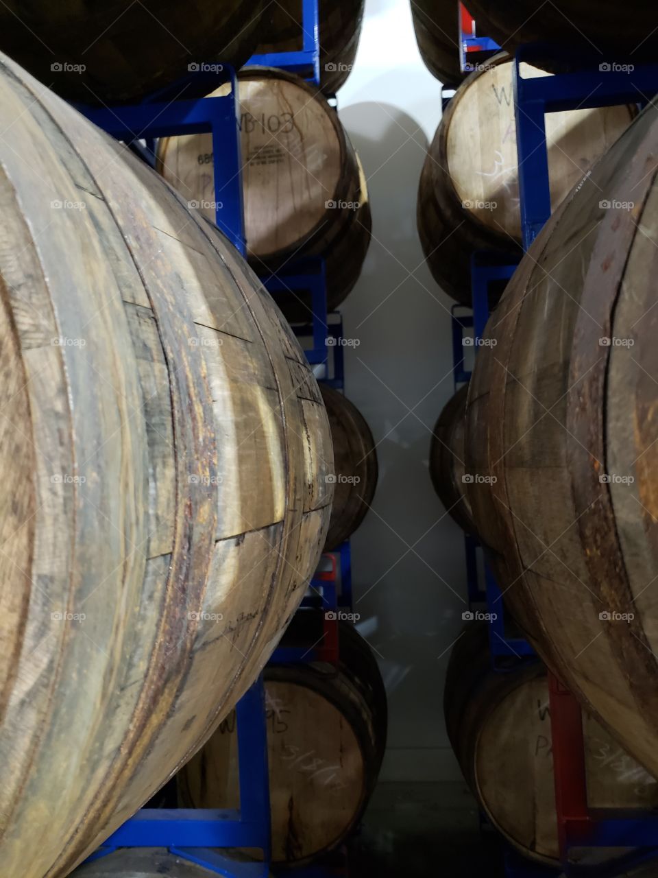 Racks on racks of different types of wooden kegs lined up, dated, and waiting to have the beer tapped and enjoyed