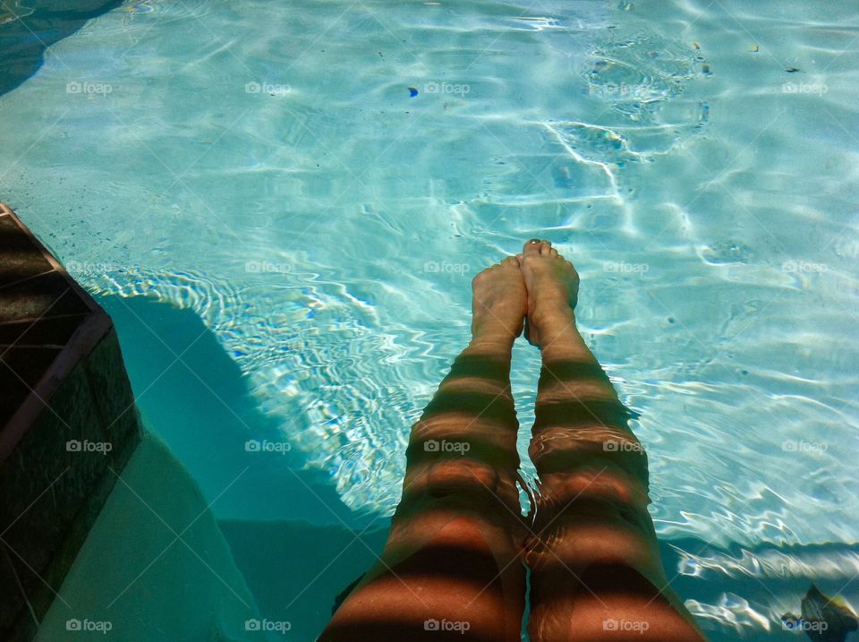 My legs in shadow, cool composition water reflection tan golden brown shapely legs poolside at home private residential pool, languorous, stretch