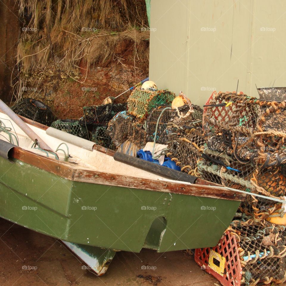 Lobster pots wedged between a wall and rowing boat