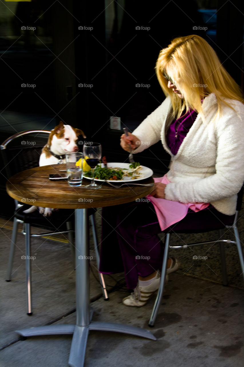 A woman eating lunch with her dog at a sidewalk table in Philadelphia 