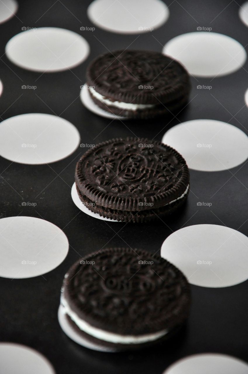 three oreo cookies black dots on black and white surface