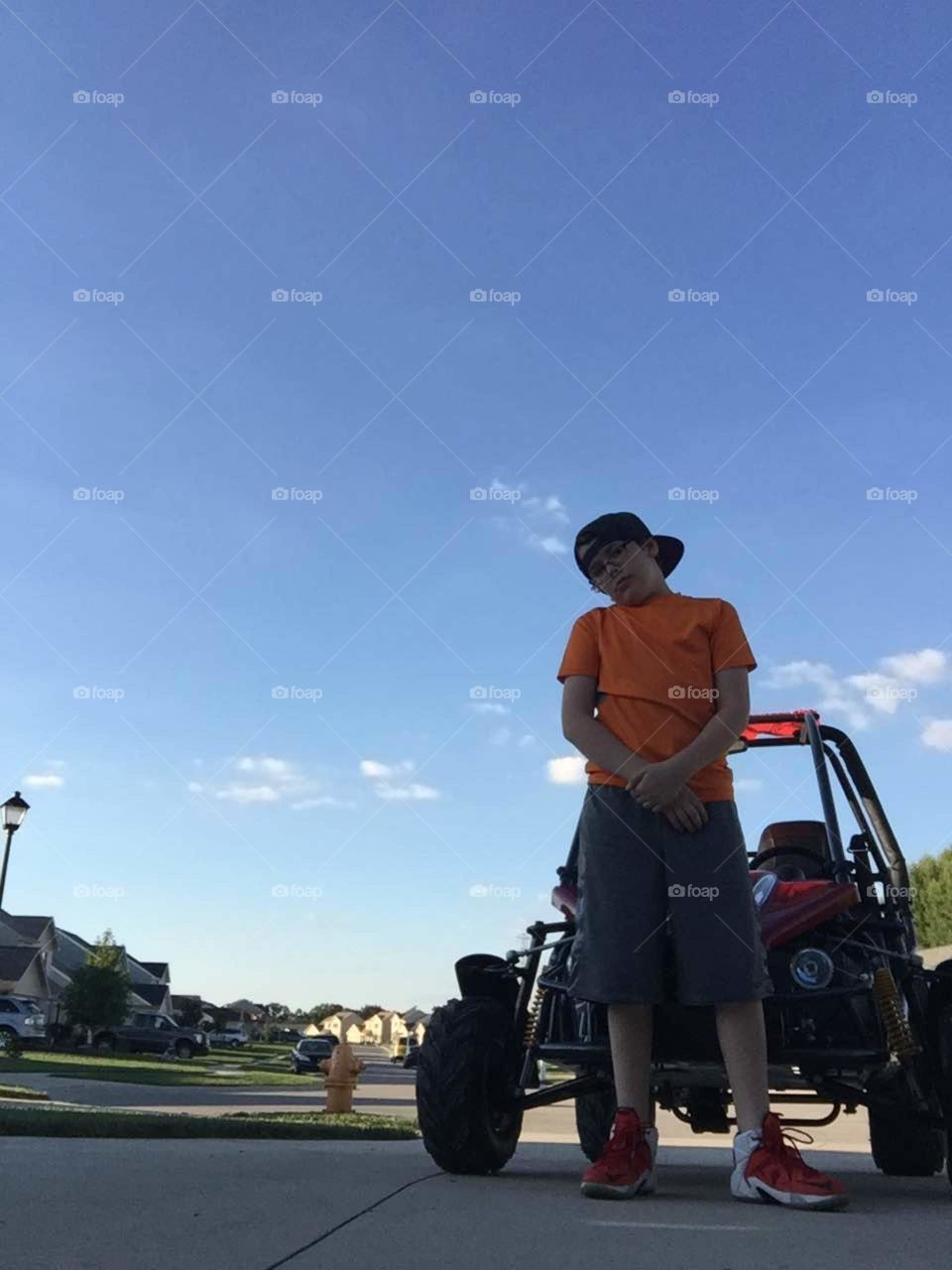 Boy standing in front of his go kart .