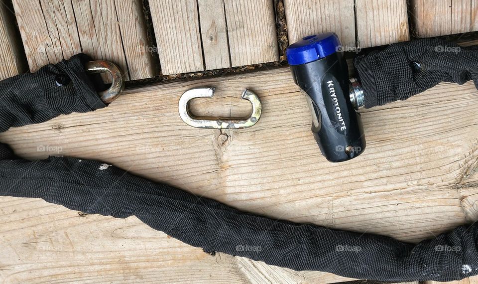 a Kryptonite bike chain cut with bolt cutters that once held a bicycle taken by thieves. a chain link is visible cut and the rest of the chain lays on the ground covered in a thick canvas cloth.
