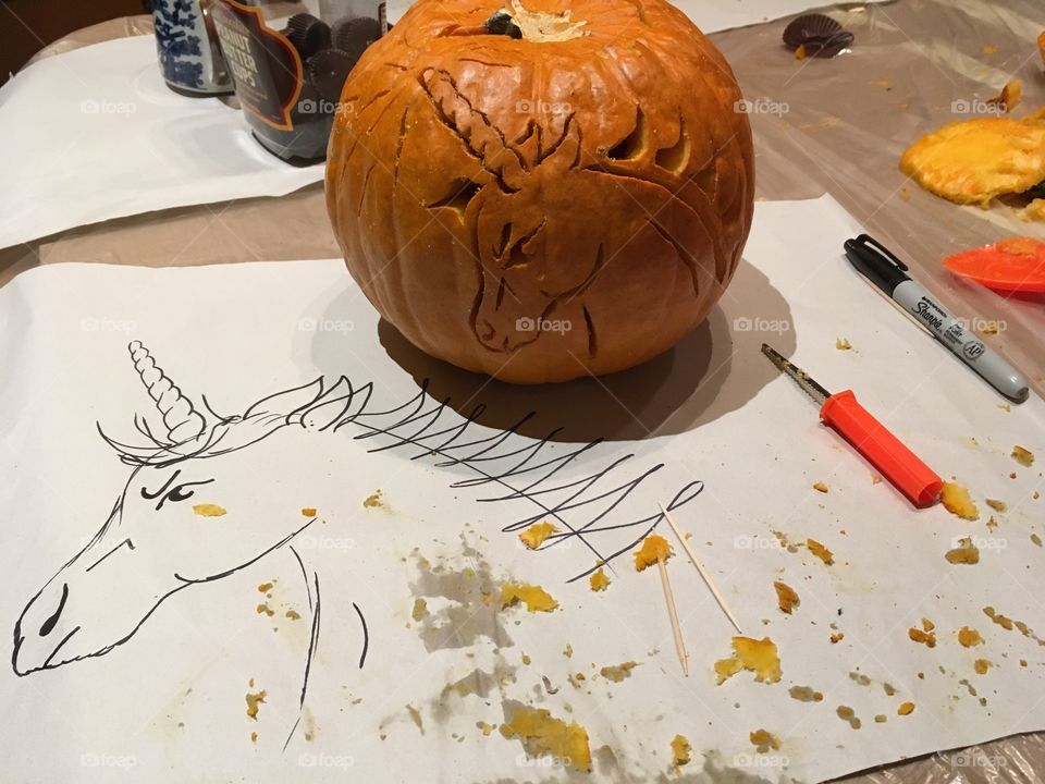 Process of carving a pumpkin with drawing and carved pumpkin on a table