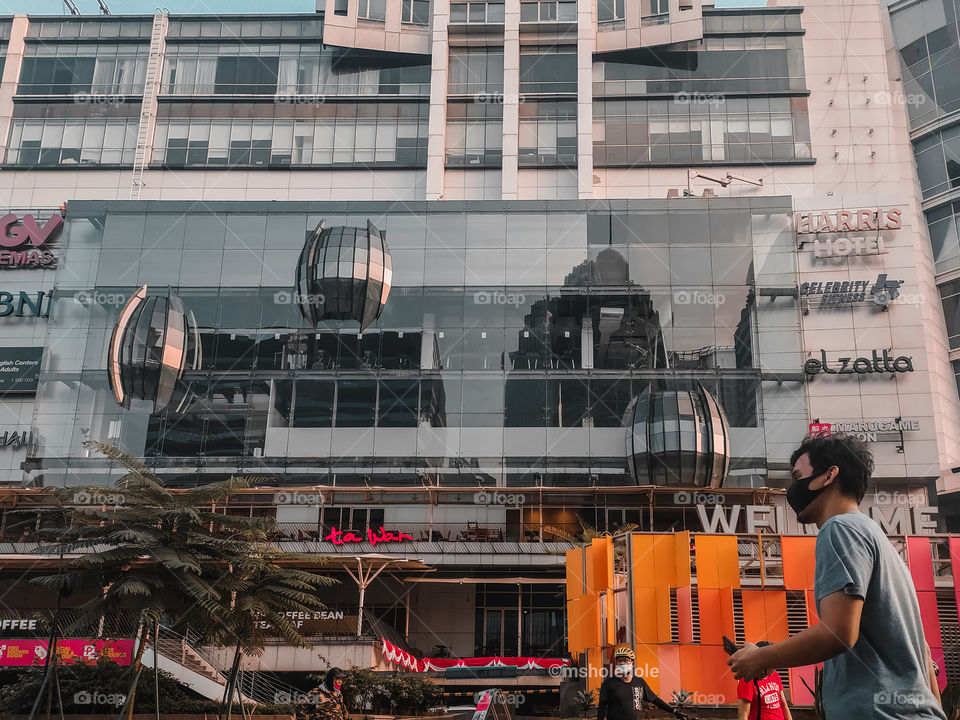 A man walking wearing a mask in front of FX Sudirman Mall, Jakarta, Indonesia.