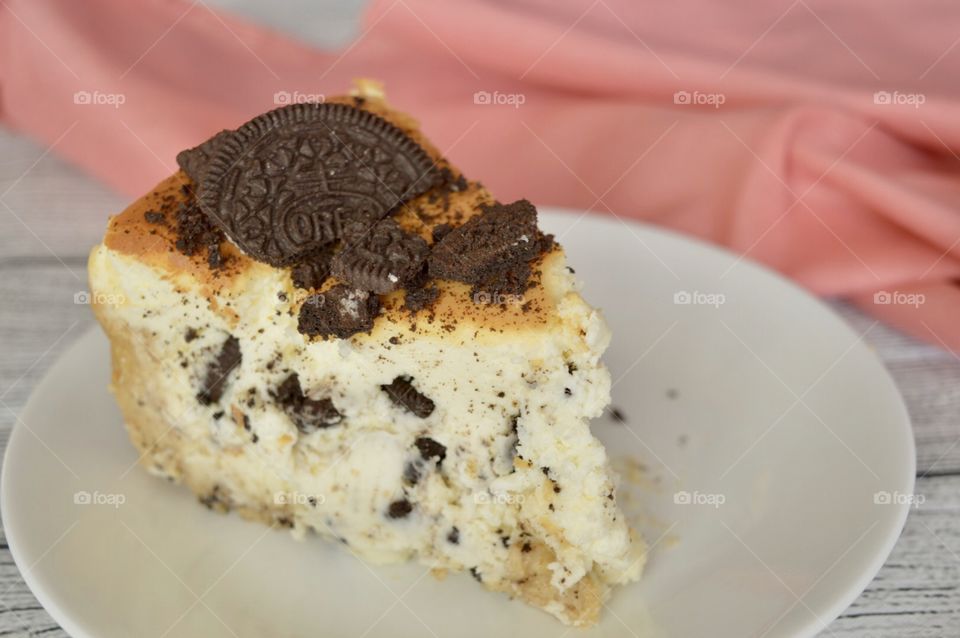 Oreo cookie cheesecake on a white plate with a pink napkin in the background
