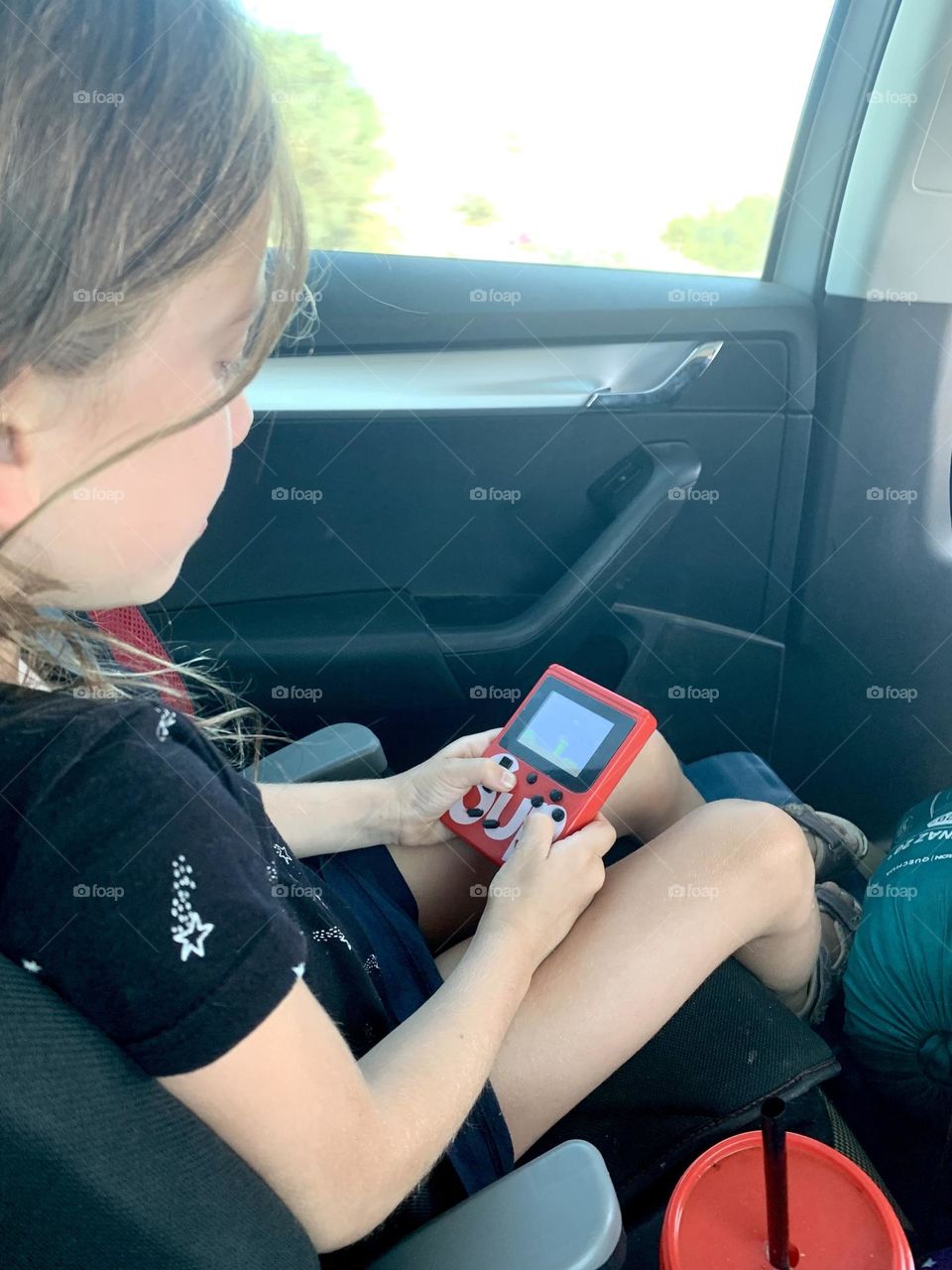 Girl playing with game console in the car
