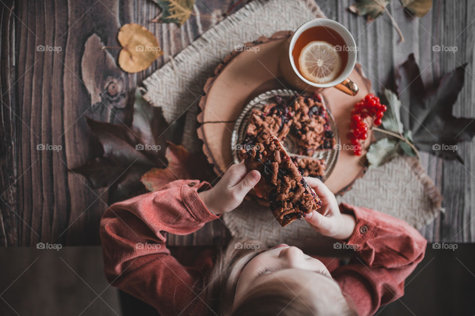 girl eats pie with berries and hot tea while sitting at a wooden table