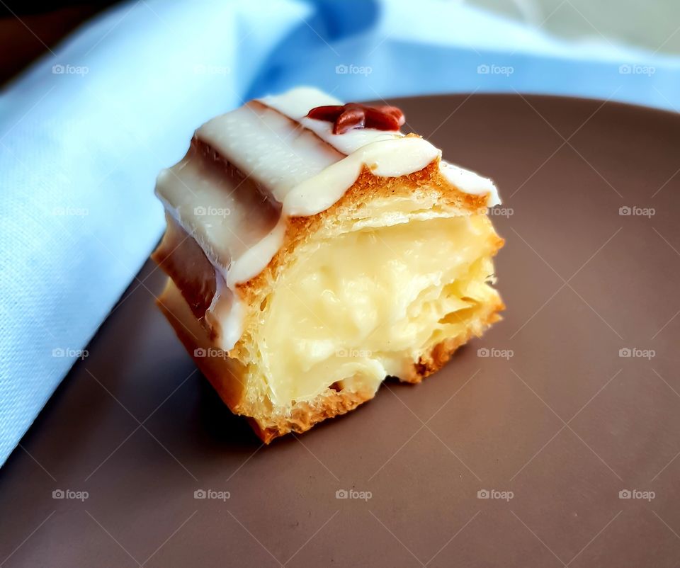 Selective focus and close-up view to slice of french dessert eclair with vanilla cream and white chocolate.