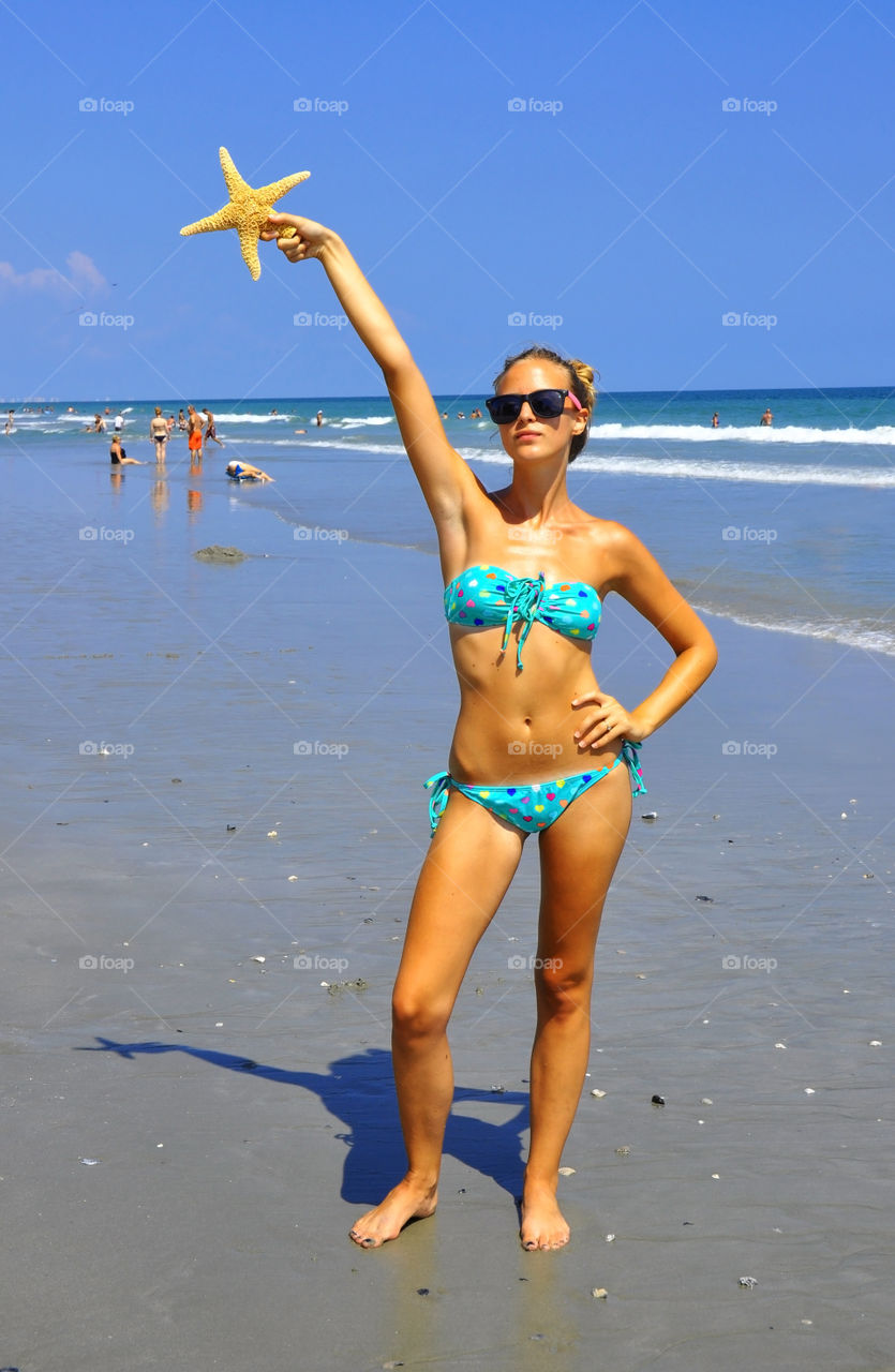 Young woman holding starfish at beach