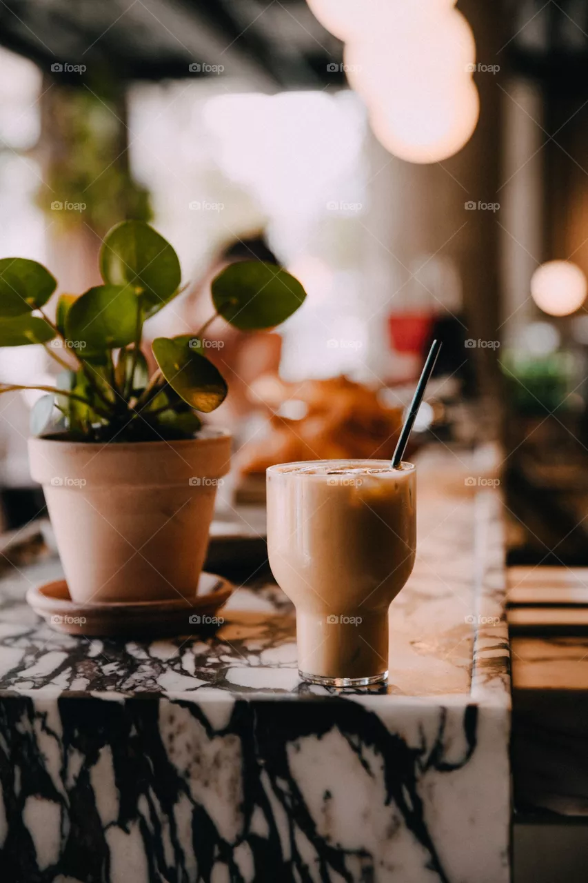 Planta cerca del café helado en mostrador del cafe