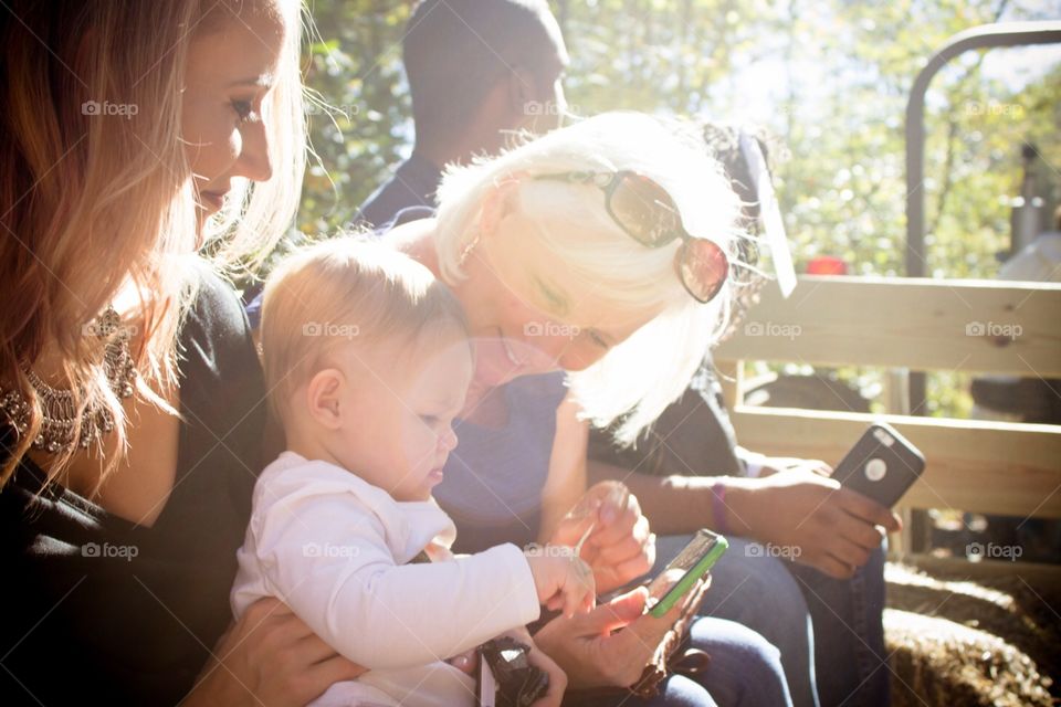 A mother watches as a grandmother and her granddaughter bond on a fall hayride. 