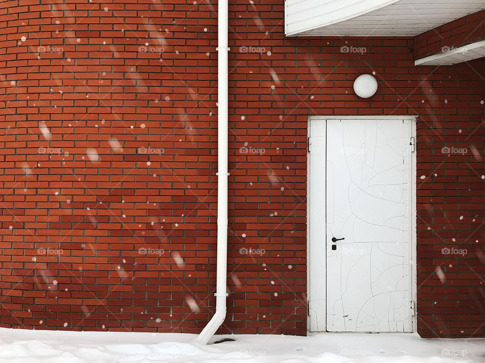 Minimalist exterior elements design of a red brick wall and white doors in winter 