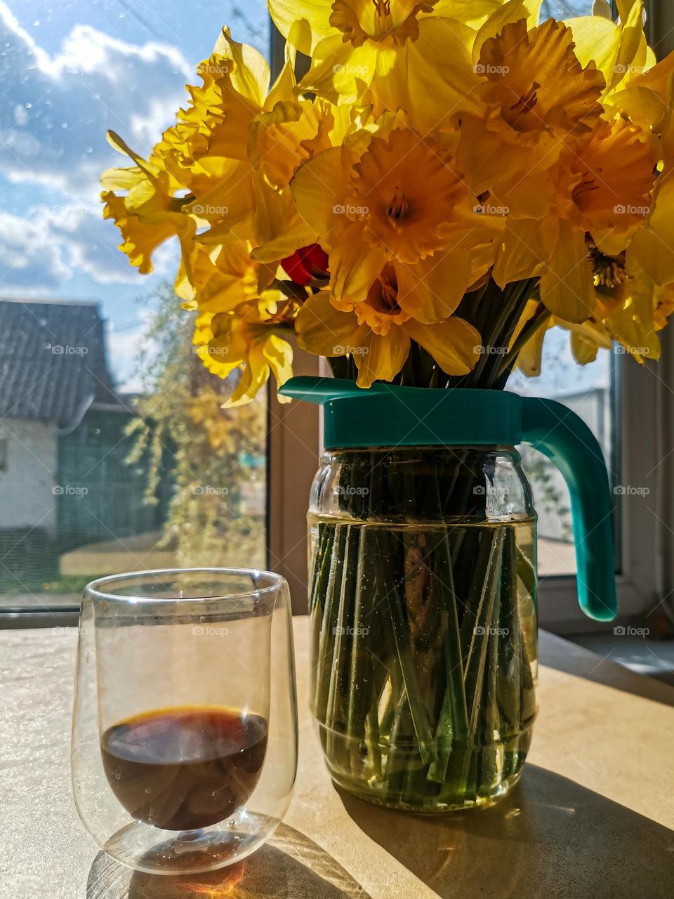 Gorgeous and vivid yellow spring flowers in a glass jar near the window and coffee at the peaceful village