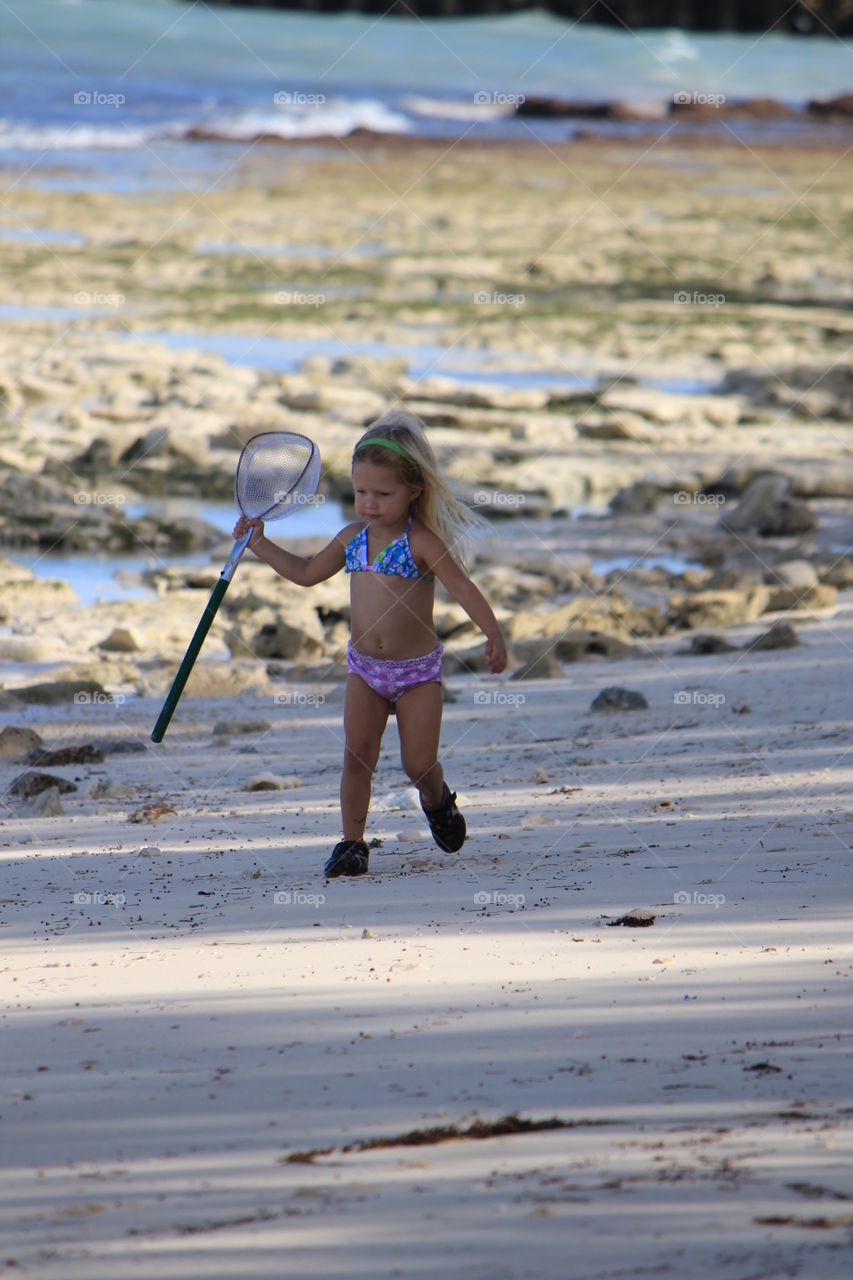 Little girl playing with net at the beach