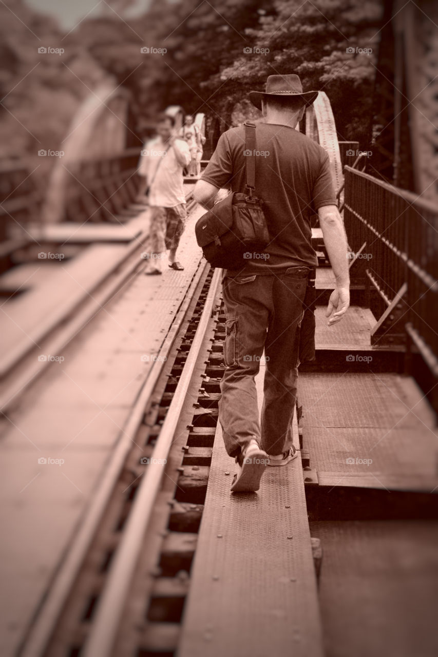 Sepia photo: Walking across the Bridge of the River Kwai, Kanchanaburi, Thailand.