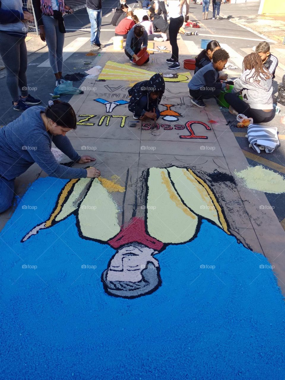 Collective art,  people of all ages making a carpet on the street with sandust