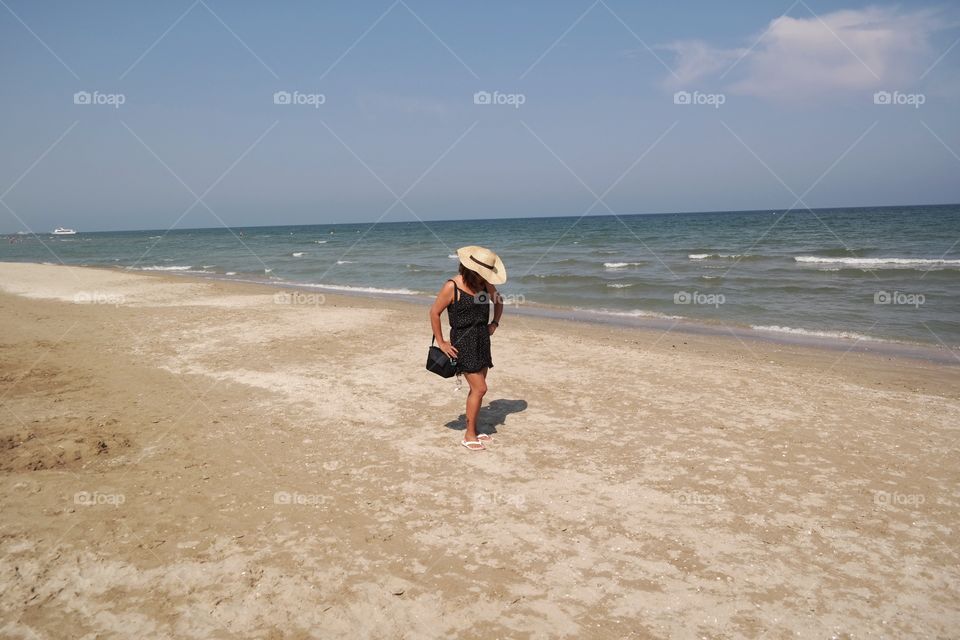 Woman with hat against the sky on the beach