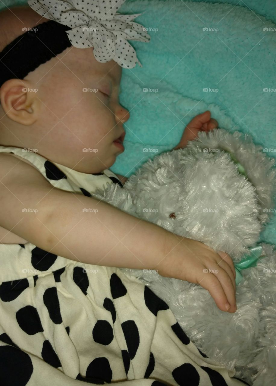 Cute baby sleeping with toy on bed
