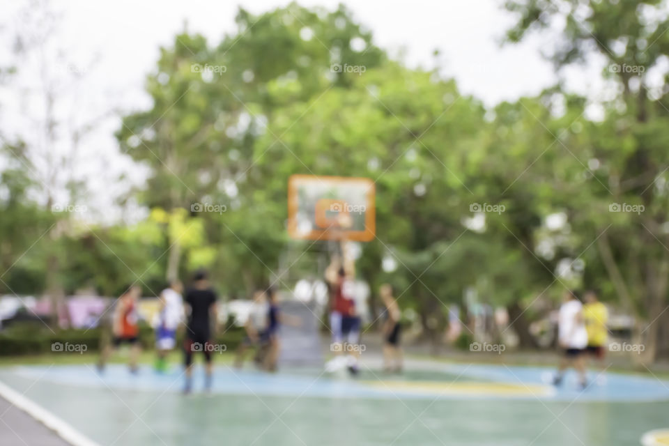 Blurry image of elderly men and teens playing basketball in the morning at BangYai Park , Nonthaburi in Thailand.