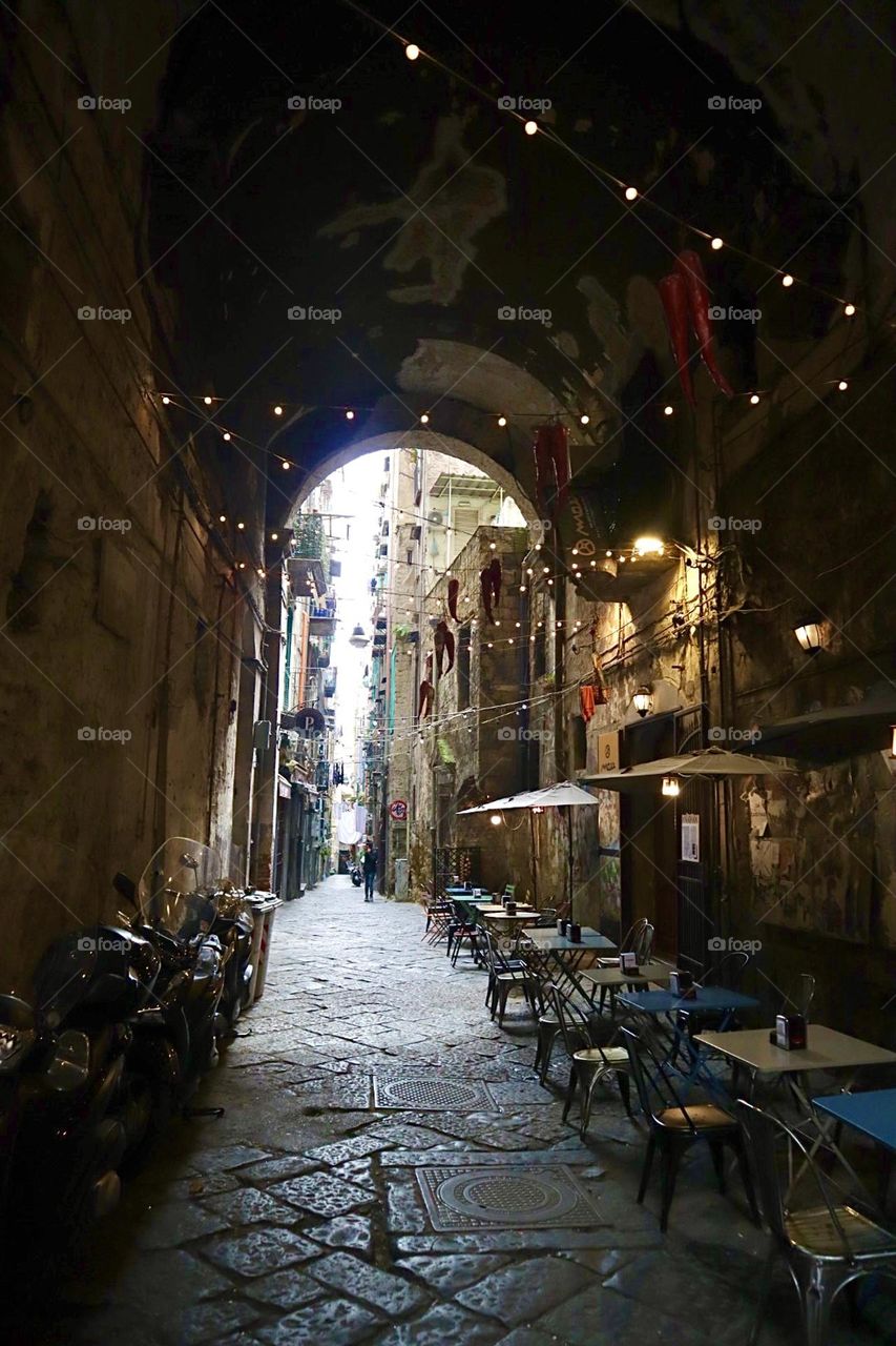 Cafe tables and chairs under the arch at Napoli streets with little light chain