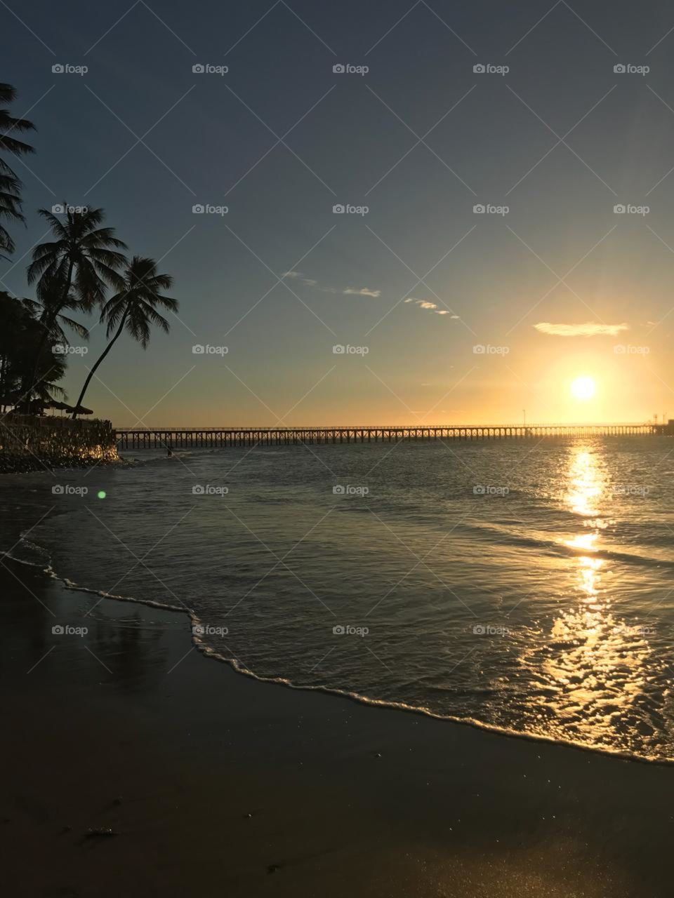 Imagem paradisíaca na praia em Paracuru Ceará Brasil. Praia da pedra rachada. Por do sol, mar, Porto, espigão, coqueiros, árvores, verde, céu, lindo, natureza, Deus. 