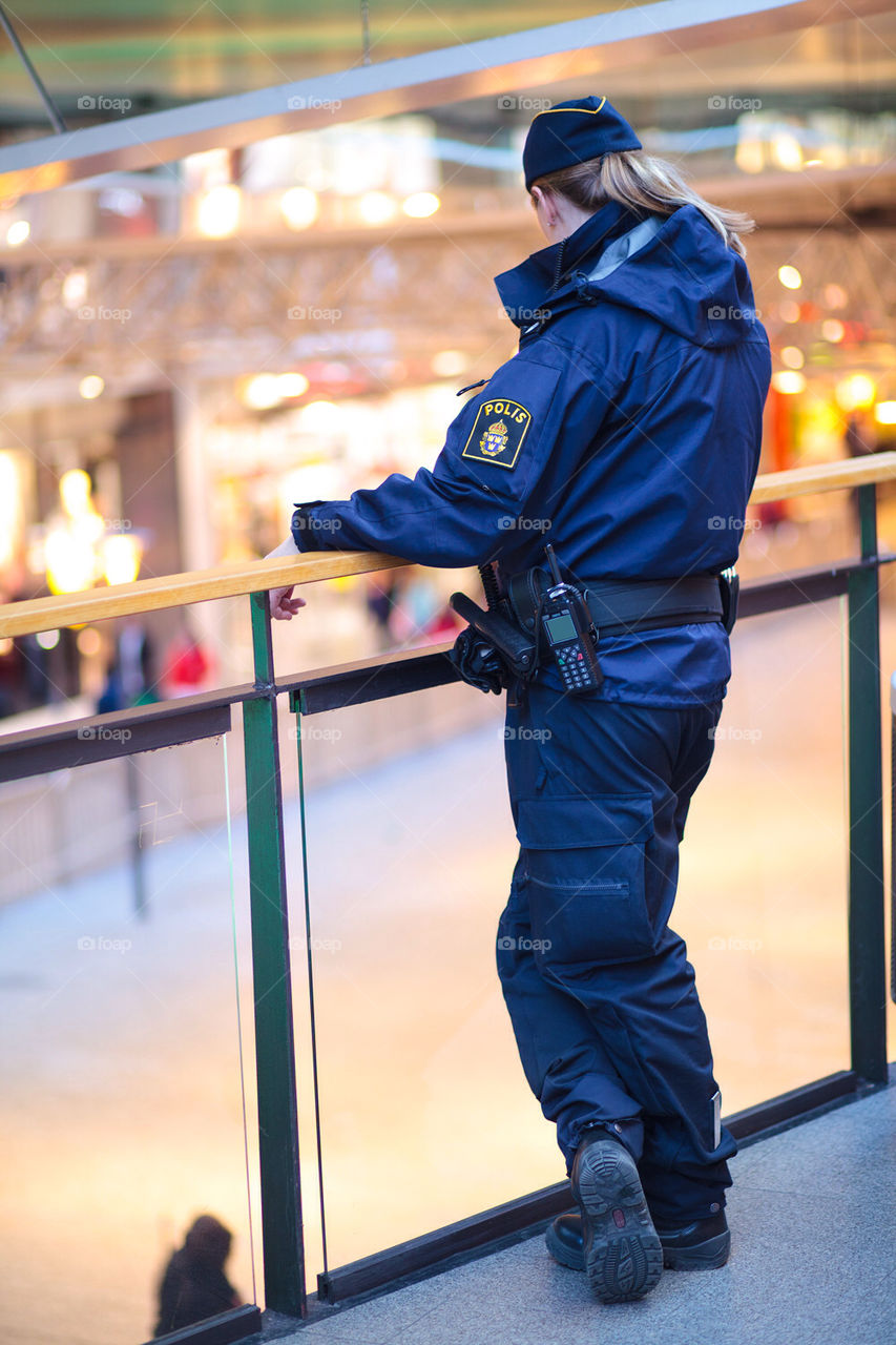 Swedish police officer watching over a mall from upper floor