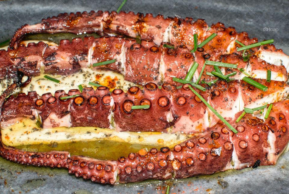 Barbacued octopus served with melted cheese and parsley