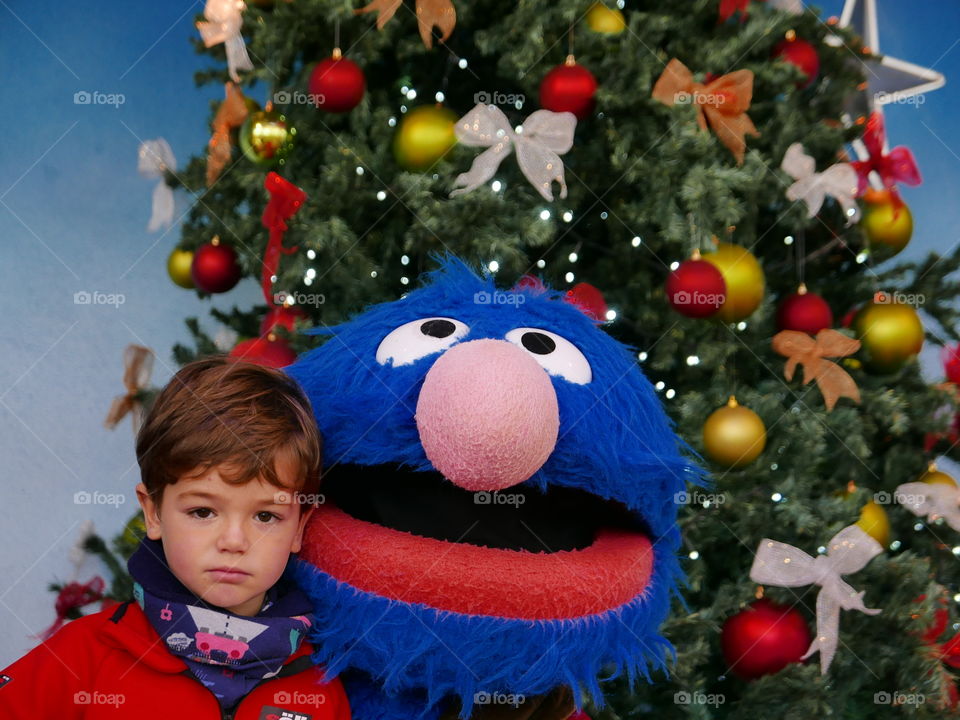 Boy standing in front christmas tree